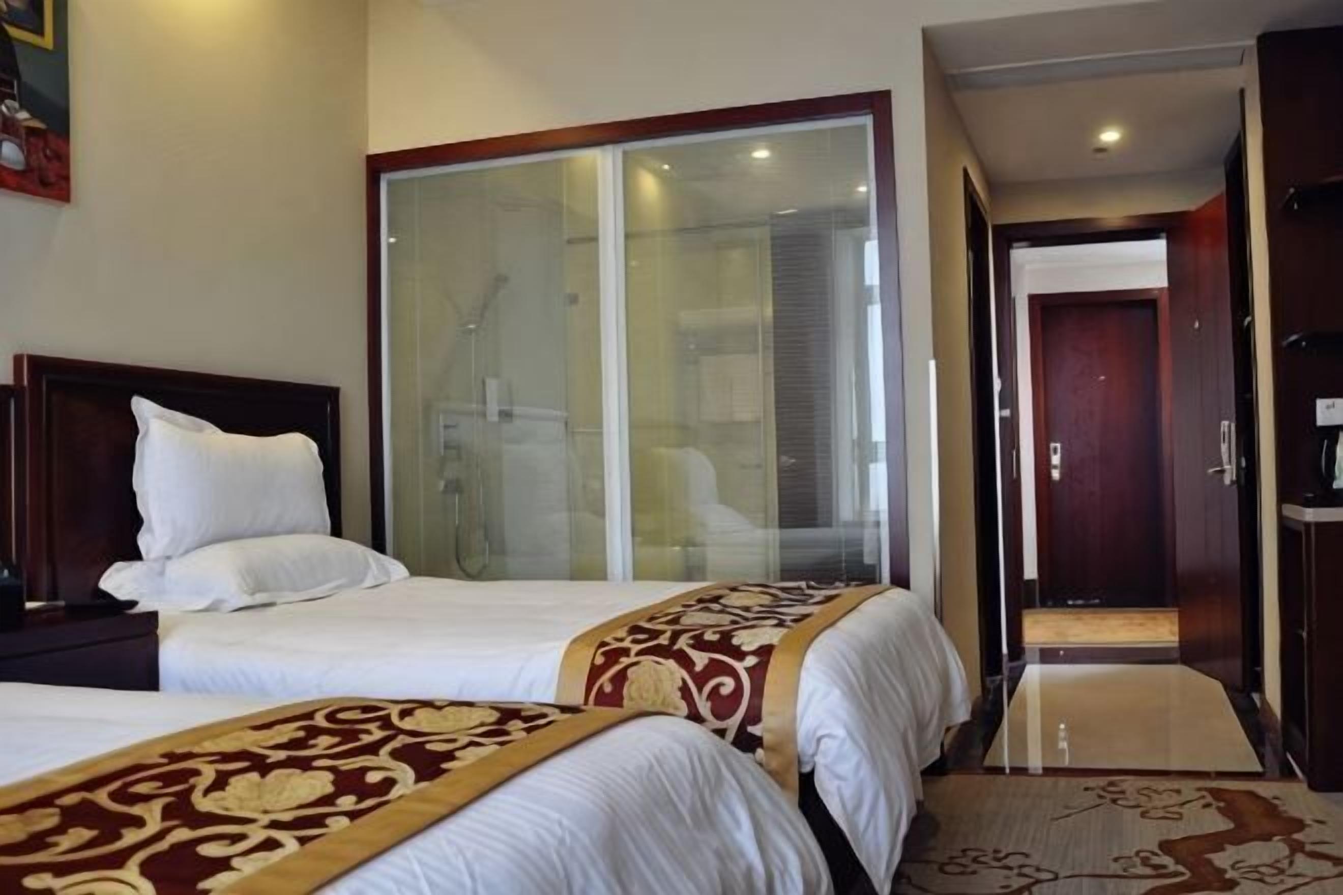 Une chambre d’hôtel avec deux lits, une douche en verre et une armoire en bois.