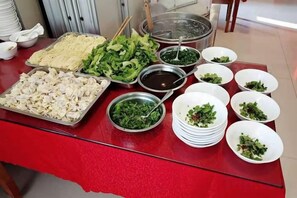 A buffet table with various food items and bowls.