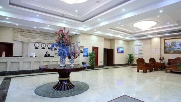 A hotel lobby with a reception desk, a large floral centerpiece, a chandelier, and a painting on the wall. - Greentree Inn Newtown Malu Subway Station Business (Shanghai)