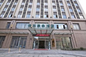 Un hotel de varios pisos con una entrada destacada y un corredor cubierto.