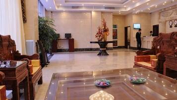 A spacious lobby with a reception desk, seating area, and a large chandelier.