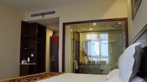 A hotel room with a bed, a wardrobe, a desk with a telephone, and a bathroom visible through a glass door. - Greentree Inn Newtown Malu Subway Station Business (Shanghai)