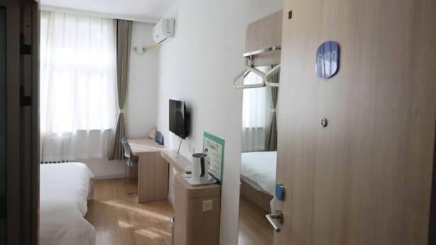 A hotel room with a bed, a desk with a chair, a TV, and a small kitchenette. - Xicui Hotel (Beijing Baizhifang) (Beijing)