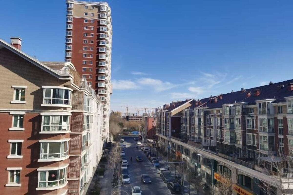 A multi-story residential building with a central courtyard, balconies, and a street view.