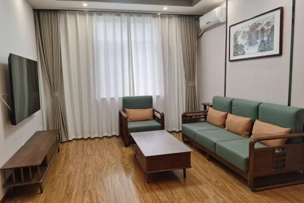 A living room with a sofa, armchair, coffee table, TV, and curtains.