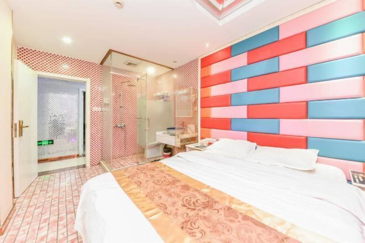 Une chambre d’hôtel comprenant un lit, une table de chevet, un miroir et un espace douche.