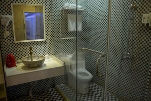 A bathroom with a checkered floor, a white sink with a red soap dispenser, a glass-enclosed toilet, and a shower area. - C8 Chain Hotel (Shanghai)