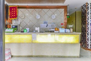 A hotel reception area with a marble counter, clocks, and a red banner. - C8 Chain Hotel (Shanghai)
