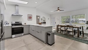 Une cuisine moderne dotée d’un îlot central, d’un four encastré et d’un ventilateur de plafond.
