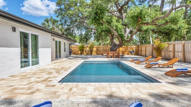 Un jardin avec une piscine, des chaises longues et une terrasse en bois.