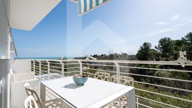 A balcony with a white table and chairs, a bowl of fruit, and a view of the sea and greenery. - In an enchanting location, in a residential neighborhood a stone's throw from the city center and directly in the territory of the Marine Protected Area Torre del Cerrano, the I Gabbiani residence will offer you a relaxing holiday. The three-room apart (Foggetta)