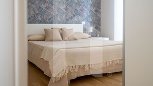 A bedroom with a bed, a nightstand, and a wall with a leaf pattern. - In an enchanting location, in a residential neighborhood a stone's throw from the city center and directly in the territory of the Marine Protected Area Torre del Cerrano, the I Gabbiani residence will offer you a relaxing holiday. The three-room apart (Foggetta)