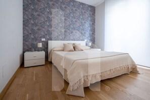 Ein Schlafzimmer mit einem Bett, Nachttischen und einer Wand mit Muster.