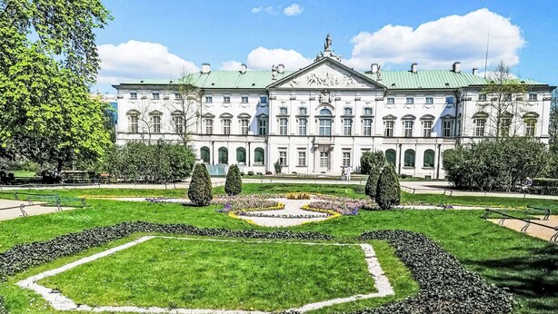 Un grand bâtiment de style classique, doté d’une façade symétrique, d’une entrée centrale et d’un jardin à la française situé devant.