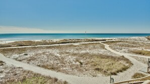 A beach with a clear sky, sandy paths, and dunes.