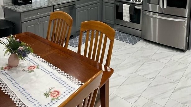 A modern kitchen with grey cabinets, stainless steel appliances, and a dining area with a wooden table and chairs. - North End Relaxing Family (Manchester)