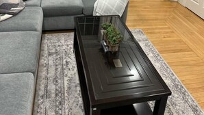 A living room with a grey sofa, a glass coffee table with a plant, and a wooden floor. - North End Relaxing Family (Manchester)