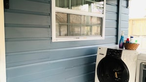 A laundry room with a washing machine and dryer, a window, and a wall-mounted light fixture. - The Studio on 8th, Entire guest suite in Wauchula Florida ! (Wauchula)