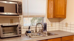 A kitchen with wooden cabinets, a stainless steel microwave, a toaster oven, a sink, and a window with blinds. - The Studio on 8th, Entire guest suite in Wauchula Florida ! (Wauchula)