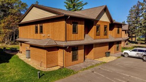 A two-story wooden house with a garage, a covered porch, and a driveway. - Lakeview Home with Dock on the Whitefish Chain, Outdoor Pool, Pickleball & More (Pequot Lakes)