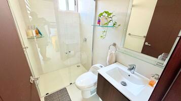 Un bagno moderno con box doccia in vetro, un water bianco e un lavandino bianco con uno specchio sopra.