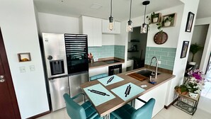 Eine moderne Küche mit einem eingebauten Kühlschrank, einer Spüle und einem Essbereich mit türkisfarbenen Stühlen.