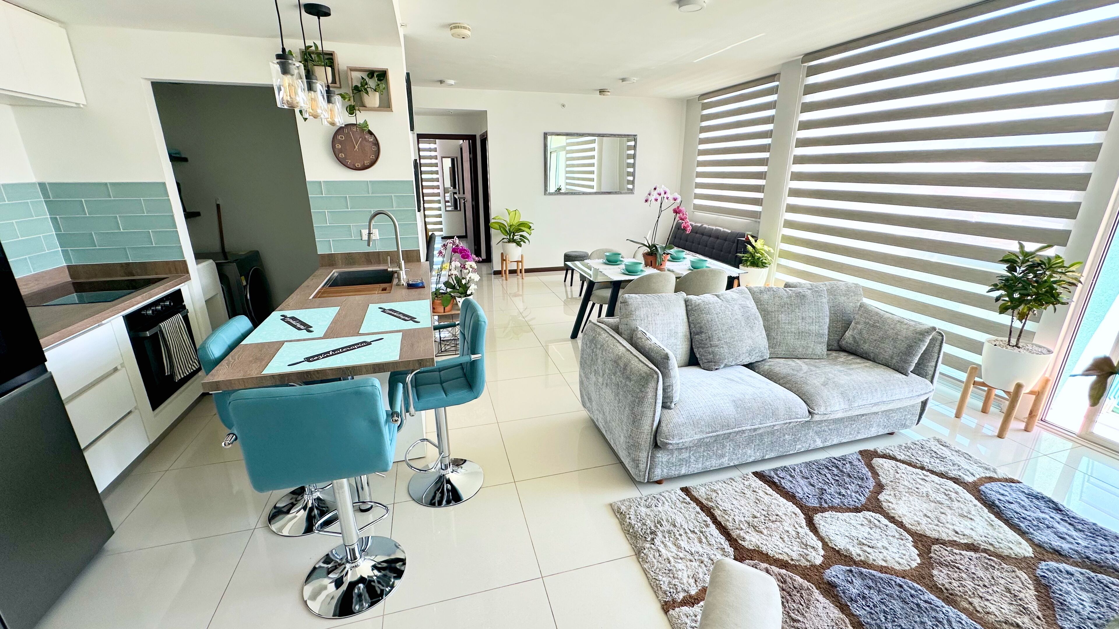 A modern living room with a grey sofa, a coffee table, and a dining area with a table and chairs.