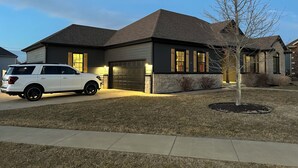 A modern two-story house with a garage, a driveway, and a tree in the front yard.