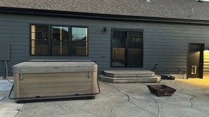 A house with a large patio, a hot tub, and a covered outdoor seating area.