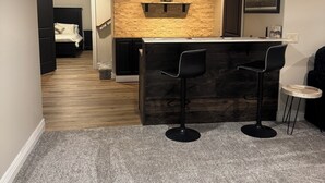 A modern kitchen with a stone backsplash, a bar area with two stools, and a dining table.