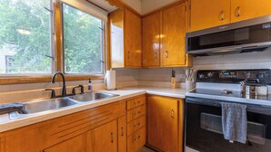 A kitchen with wooden cabinets, a stainless steel sink, a microwave, and an oven. - Ely Basecamp- Perfect for Families and Groups (Ely)