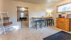 A modern kitchen with a wooden bar counter, black stools, and a coffee station. - Ely Basecamp- Perfect for Families and Groups (Ely)