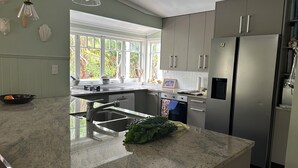 Una cocina moderna con una isla grande, electrodomésticos de acero inoxidable y vistas a zonas verdes.