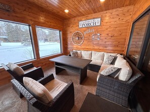 Ett mysigt rum med träväggar, en soffa, ett bord och en skylt med texten ”Välkommen till The Porch”.