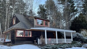 Une maison en bois à deux étages, dotée d’un porche couvert et d’un garage.