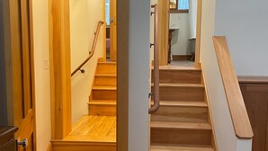 Un escalier en bois, doté d’une rampe, mène à l’étage supérieur.