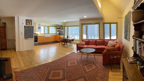Un vaste espace de vie comprenant un canapé rouge, une table basse et un tapis à motifs.