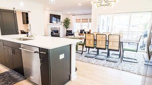 Een moderne keuken met een inbouwkookeiland, een eethoek met rieten stoelen en uitzicht op de omgeving.