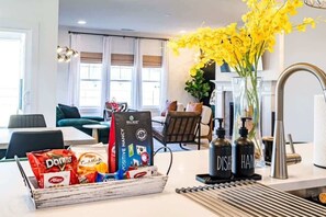 Una cuina amb zona de menjador, una màquina de cafè i un ram de flors grogues.