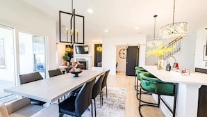 A modern kitchen with a dining area, a staircase, and a view of the city. - Brand New-Downtown Apex-4BD/4BA-Gameroom-2 Kings! (Apex)