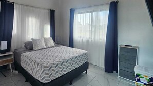 A bedroom with a bed, a nightstand, a dresser, and an air conditioning unit.