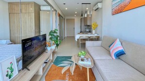 Ein modernes Wohnzimmer mit Fernseher, Sofa und Essbereich.