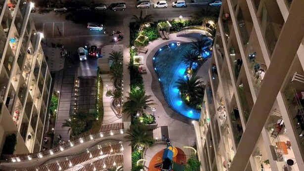 Ein mehrgeschossiges Atrium mit einem zentralen Pool, Außenmöbeln und einem Spielbereich für Kinder.