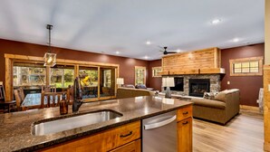 Una cocina amplia con encimeras de granito, lavavajillas integrado y chimenea de piedra.