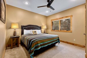 A bedroom with a bed, two bedside lamps, a ceiling fan, a window with a view, and a carpeted floor. - Lakeview Home with Dock on the Whitefish Chain, Outdoor Pool, Pickleball & More (Pequot Lakes)