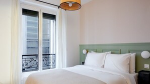 A hotel room with a bed, a window with a view, and a hanging lamp. - Blueground | Ternes, elevator & w/d, nr Arc (Paris)