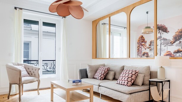 A modern living room with a sofa, armchair, coffee table, and a large mirror. - Blueground | Ternes, elevator & w/d, nr Arc (Paris)