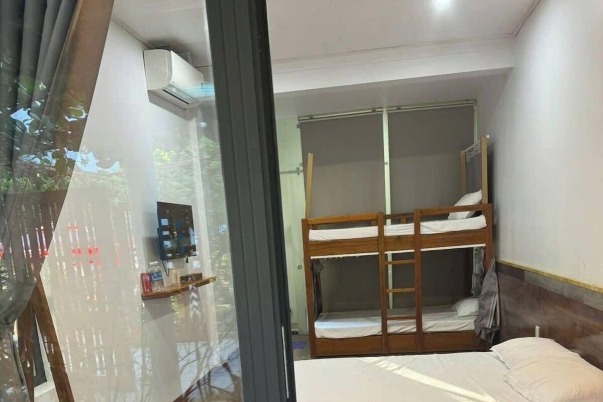 A bedroom with a bunk bed, a desk with a chair, and an air conditioning unit on the wall.
