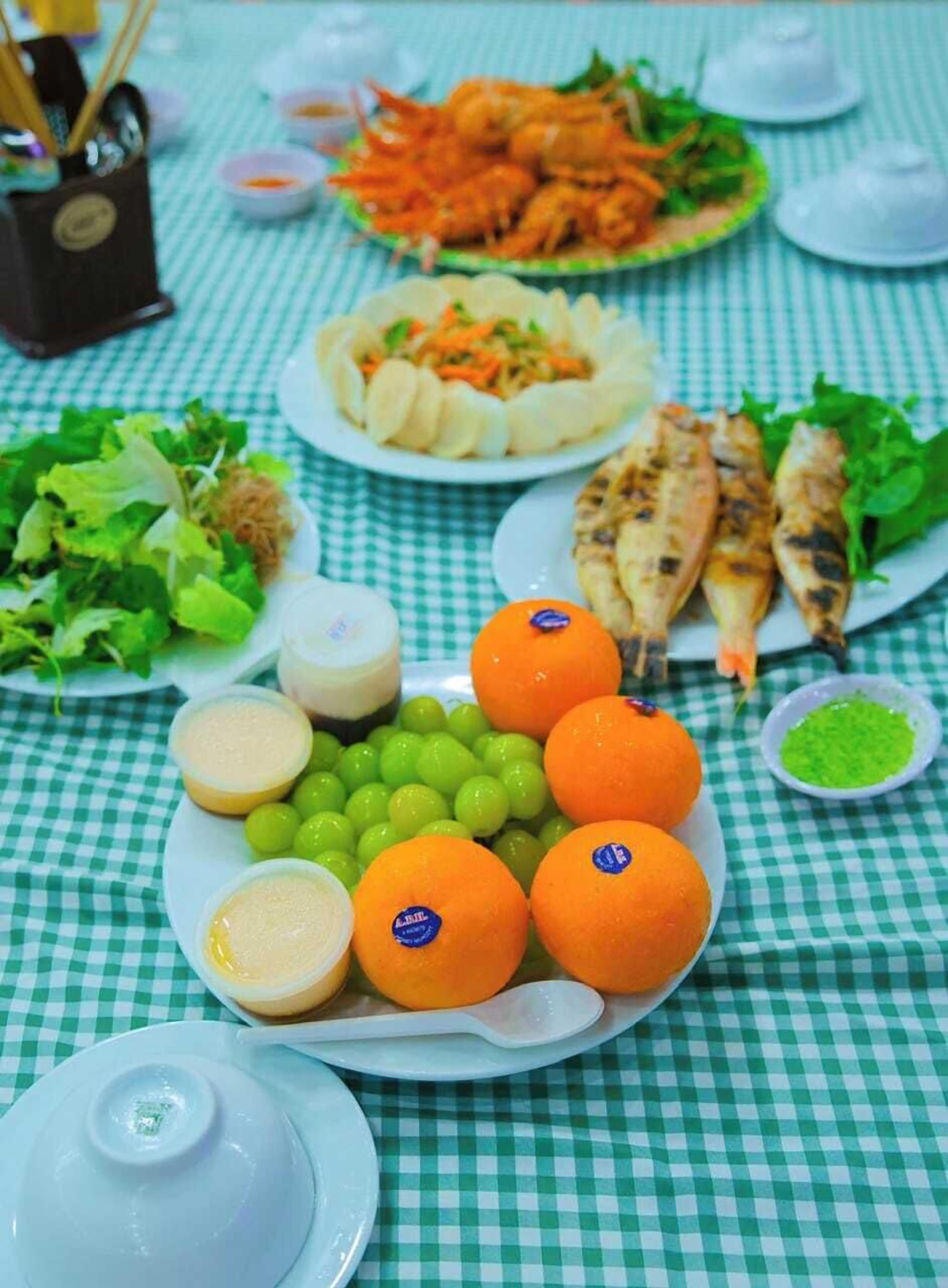 A table with various dishes including grilled fish, vegetables, and fruits, suggesting a meal setup.