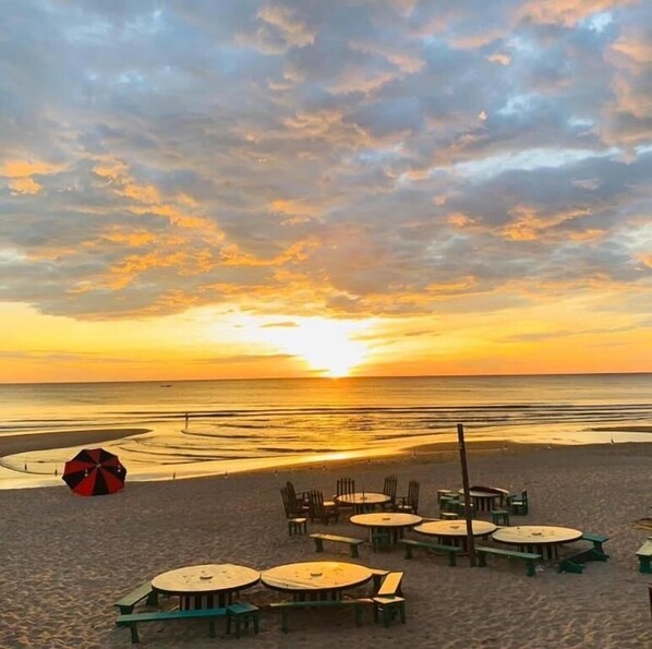 A beach with tables and chairs arranged for dining, overlooking the ocean at sunset. - Seasand Quang Binh - by BAY LUXURY (Dong Hoi)